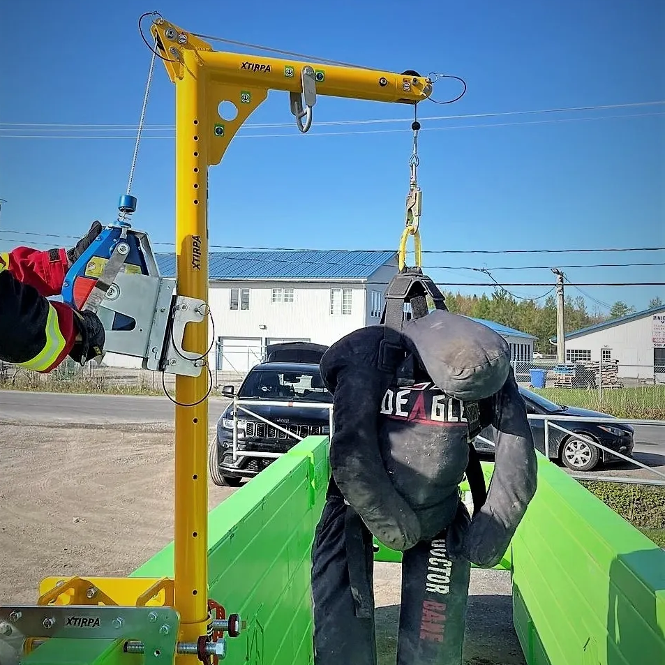 Un dispositif de levage jaune portatif XTRIPA utilisé pour soulever un sac de poids lourd dans un environnement extérieur, démontrant un équipement de manutention industriel avec des fonctionnalités de sécurité et d'efficacité pour des opérations de levage.